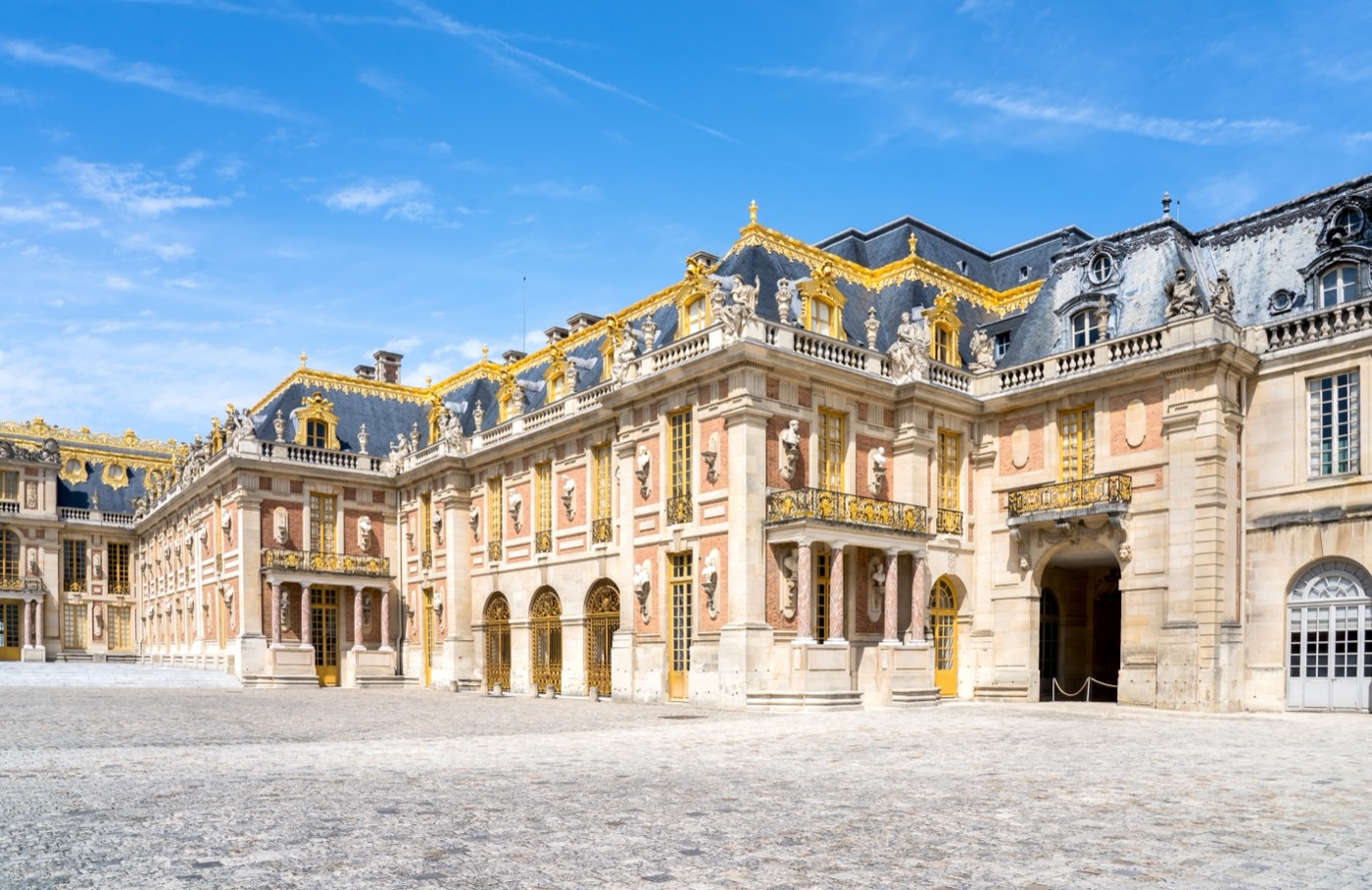 Die goldverzierte Barockfassade am Marmorhof (Cour de Marbre) des Schlosses Versailles mit rot-weißem Mauer